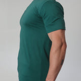 A side on view of a tall broad guy wearing a 2XL tall slim t-shirt.