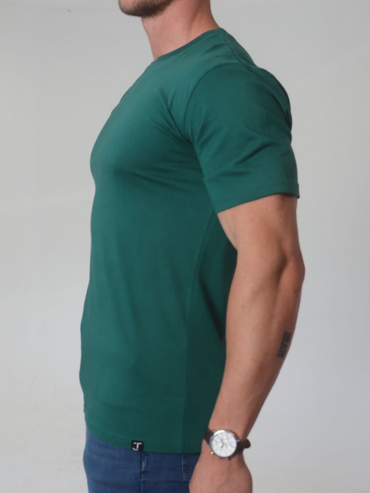 A side on view of a tall broad guy wearing a 2XL tall slim t-shirt.