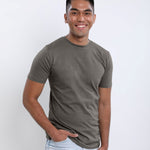 A tall slim guy wearing a dark grey medium tall t-shirt, hand in pocket.