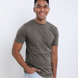 A tall slim guy wearing a dark grey medium tall t-shirt, hand in pocket.