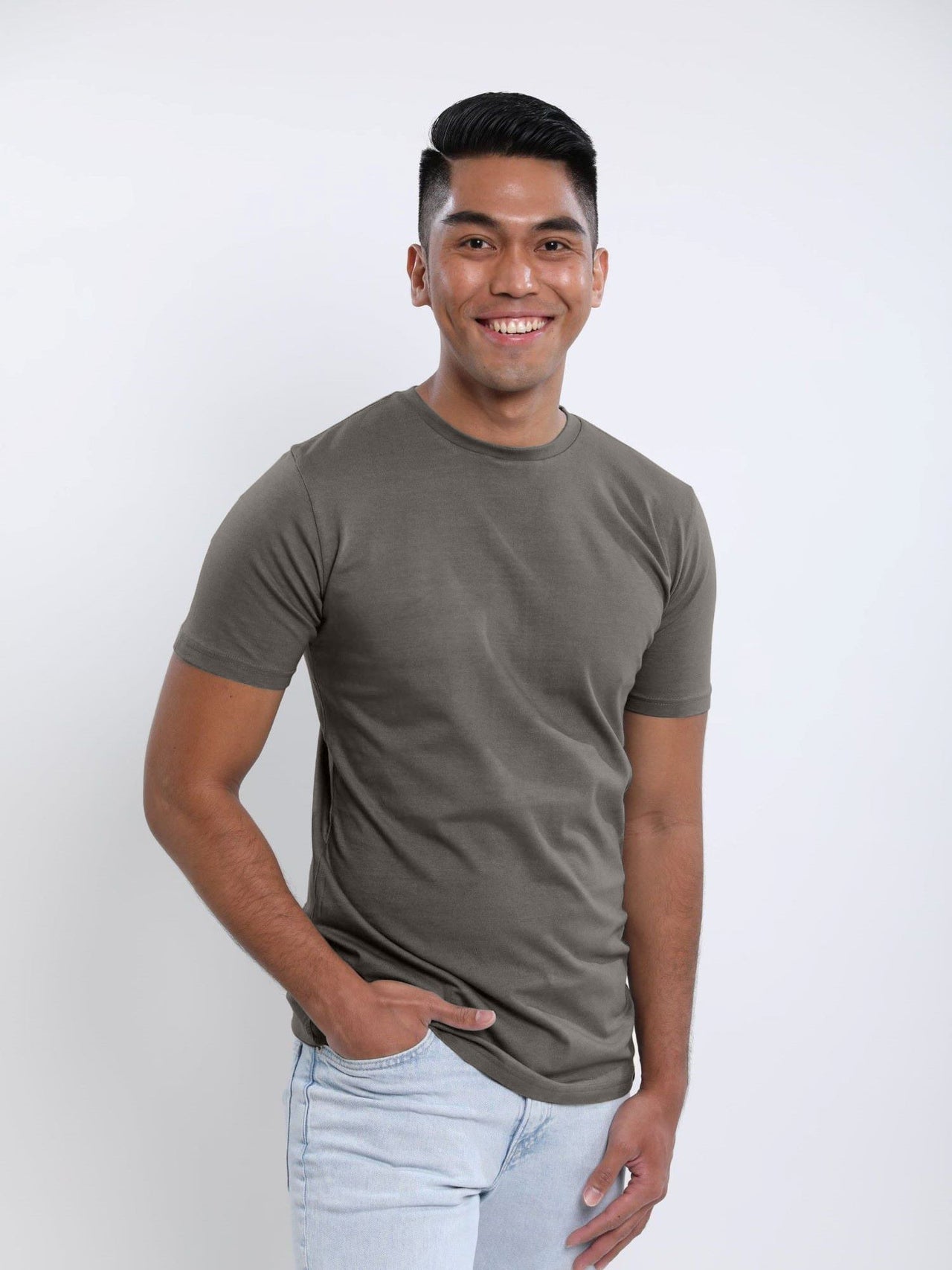 A tall slim guy wearing a dark grey medium tall t-shirt, hand in pocket.