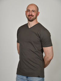 Thumbnail for A tall and slim guy in the studio, hands behind back and wearing a dark grey XL tall slim v-neck t-shirt.