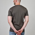 A shot from behind of a tall and slim guy in the studio and wearing a dark grey XL tall slim v-neck t-shirt.