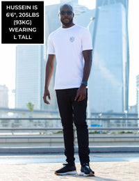 Thumbnail for A head to toe shot of a tall and skinny guy in the street and wearing a white minimal graphic tall t-shirt.