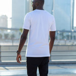 A shot from behind of a tall skinny guy in the street and wearing a white tall slim fit t-shirt.