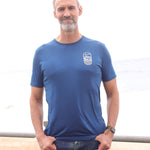 An upper body shot of a tall slim guy in an L tall graphic t-shirt with a lake design, hands in pockets.