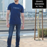 A head to toe shot of a tall and slim guy in the street and wearing a navy blue Just Tall branded graphic tall t-shirt.