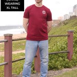 A head to toe shot of a tall skinny guy wearing an XL tall graphic t-shirt with a tree design.