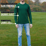 A head to toe shot of a tall athletic guy in a park wearing a dark green long sleeve tall t-shirt.