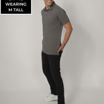 A head to toe shot of a tall skinny guy wearing a grey tall polo shirt.