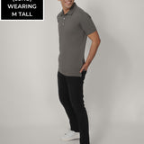 A head to toe shot of a tall skinny guy wearing a grey tall polo shirt.