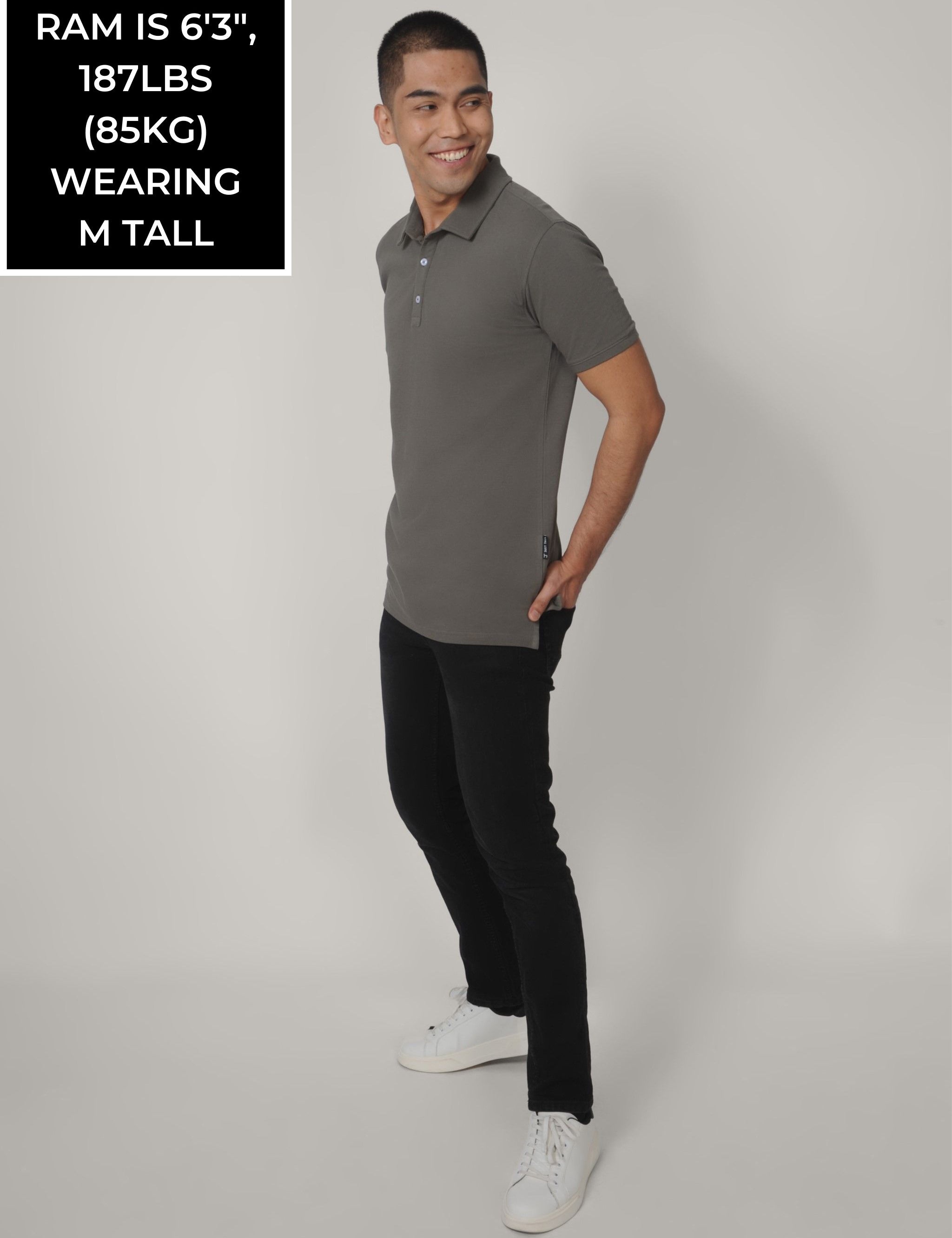 A head to toe shot of a tall skinny guy wearing a grey tall polo shirt.