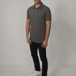 A head to toe shot of a tall skinny guy wearing a grey medium tall polo shirt.