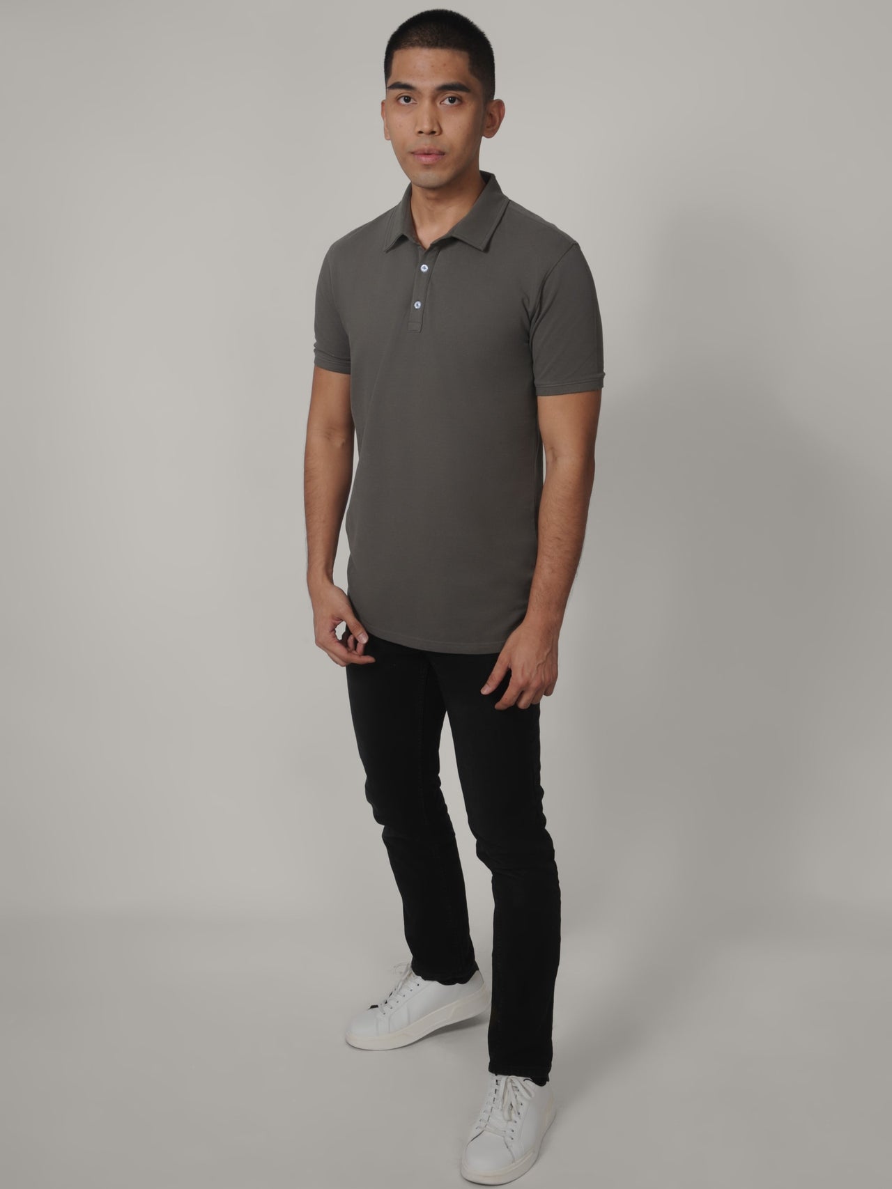 A head to toe shot of a tall skinny guy wearing a grey medium tall polo shirt.