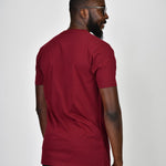 A shot from behind of a tall and slim guy in the studio and wearing a cabernet L tall slim t-shirt.