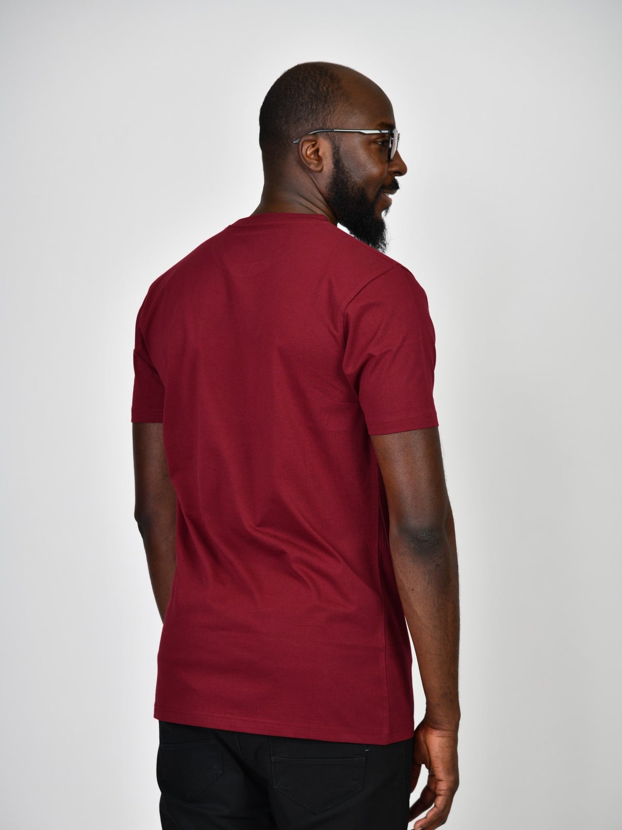 A shot from behind of a tall and slim guy in the studio and wearing a cabernet L tall slim t-shirt.
