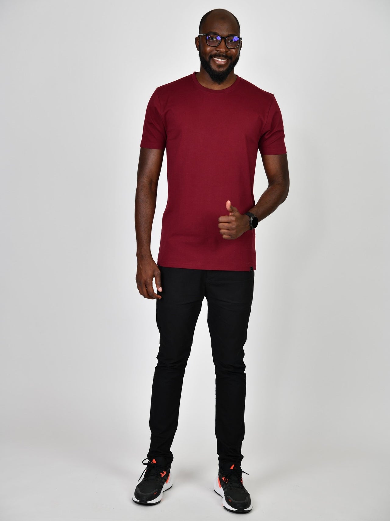 A head to toe shot of a tall and slim guy in the studio, wearing a cabernet L tall slim t-shirt and showing a thumbs up