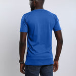 A shot from behind of a tall and athletic guy in the studio wearing a blue large tall slim t-shirt.