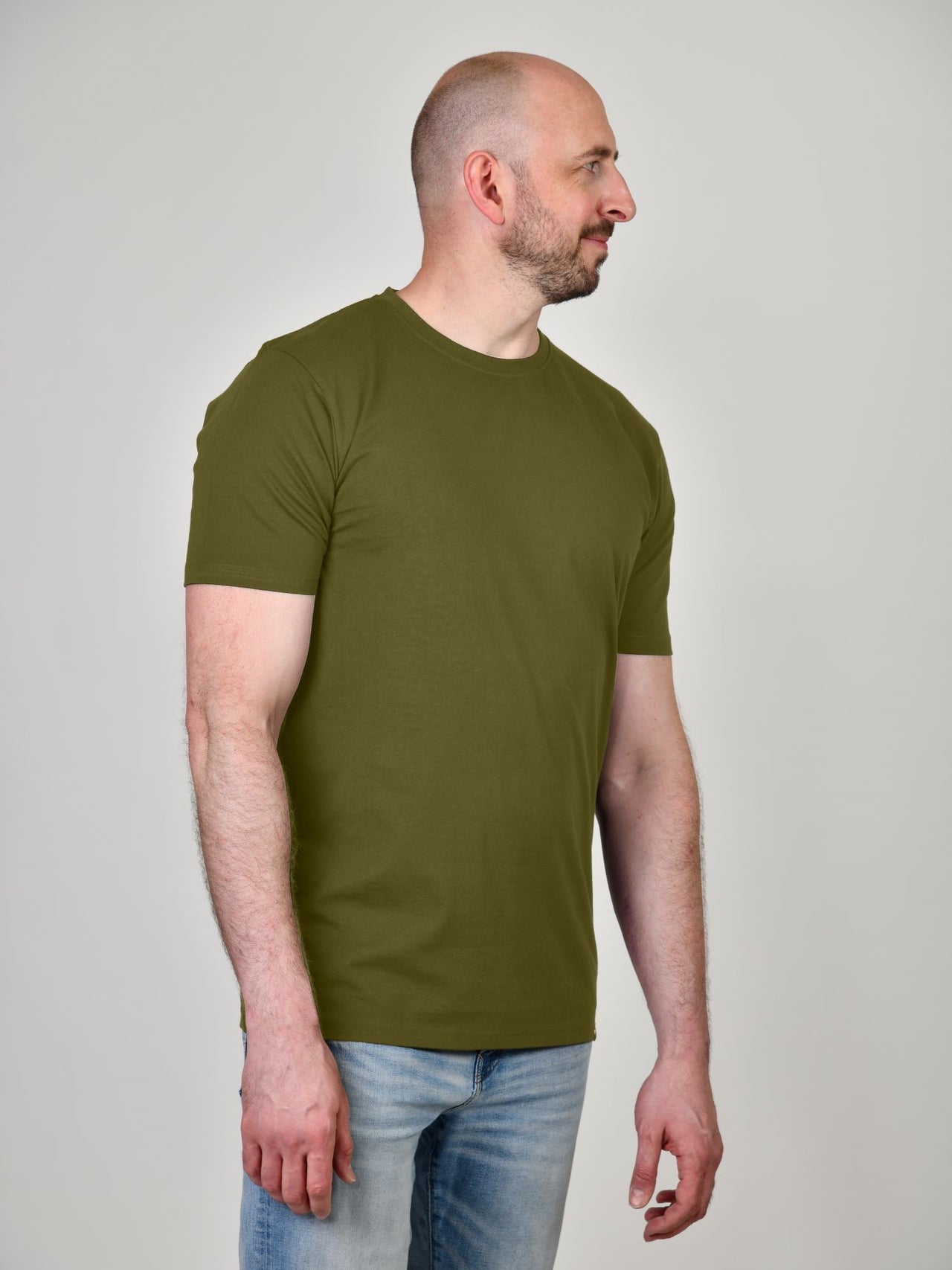 A tall athletic guy wearing a military green XL tall t-shirt and looking to the right.