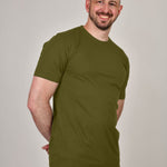 A shot of a tall athletic guy, hands behind back, wearing a military green XL tall t-shirt.