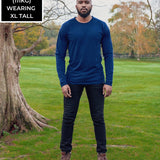 A head to toe shot of a tall athletic guy in a park wearing a navy long sleeve tall t-shirt.
