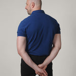 A shot from behind of a tall skinny guy wearing a XL tall navy pique polo shirt.