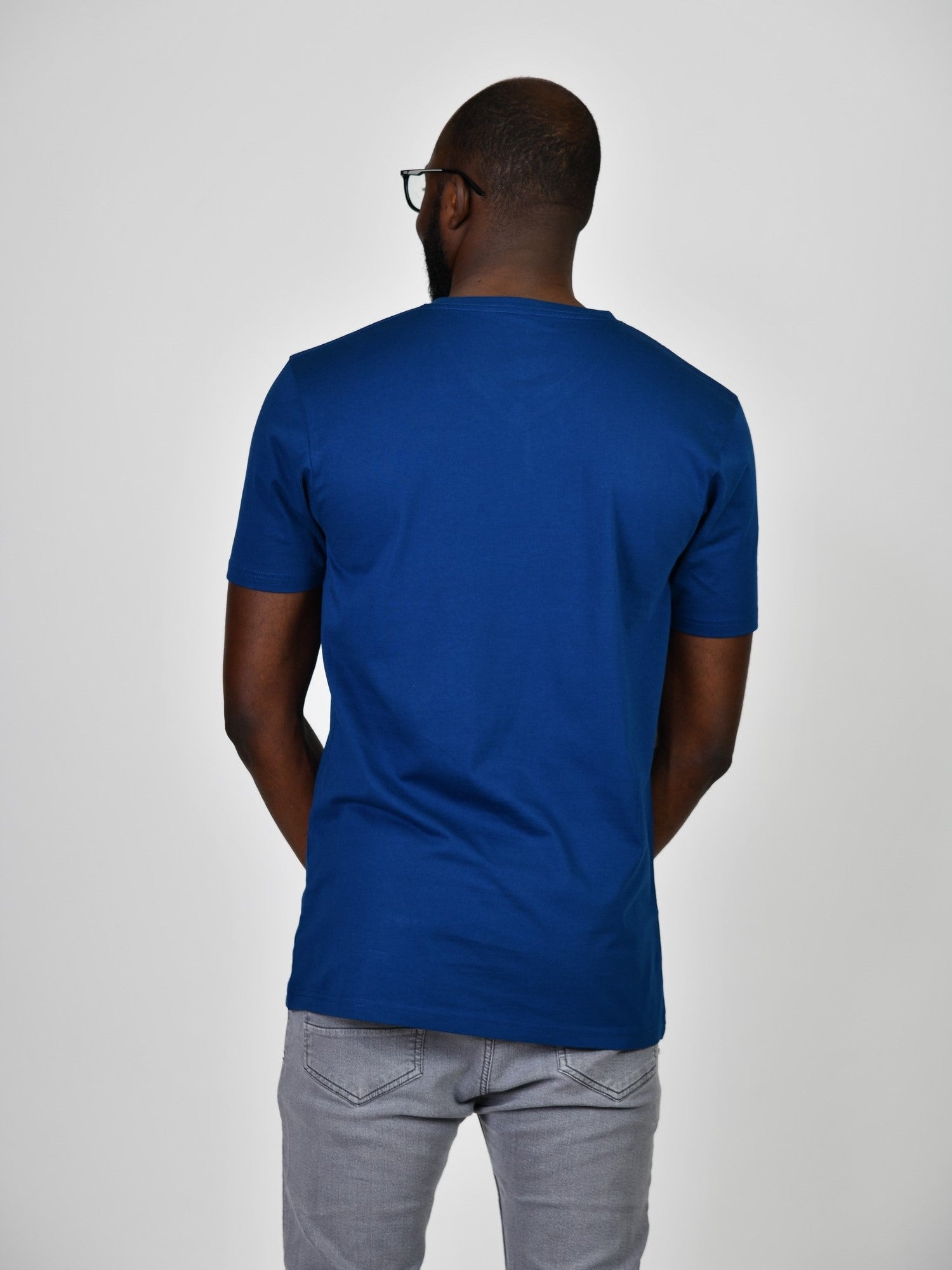 A shot from behind of a tall and slim guy in the studio and wearing a navy L tall slim t-shirt.