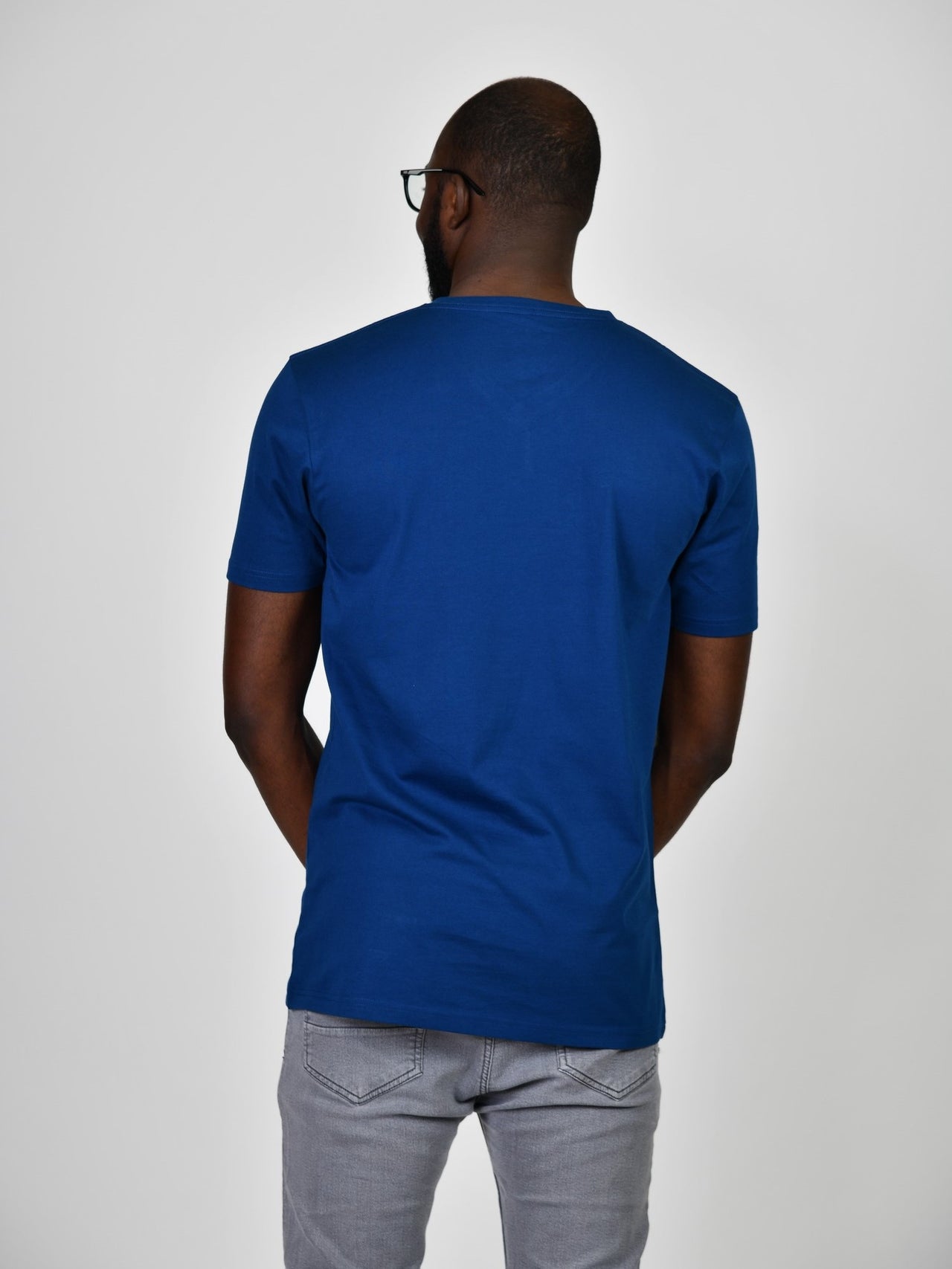 A shot from behind of a tall and slim guy in the studio and wearing a navy L tall slim t-shirt.