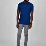 A head to toe shot of a tall and slim guy in the studio, wearing a navy blue L tall slim t-shirt.