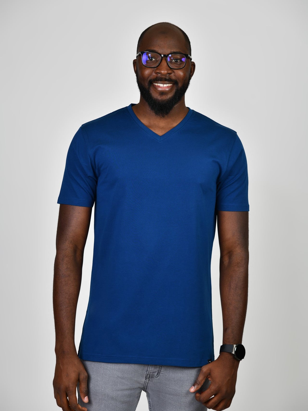 A tall and slim guy smiling in the studio and wearing a navy blue L tall slim v-neck t-shirt.