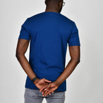 A shot from behind of a tall and slim guy in the studio and wearing a navy blue L tall slim v-neck t-shirt.