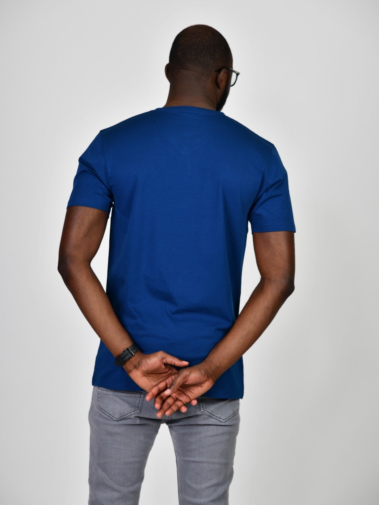 A shot from behind of a tall and slim guy in the studio and wearing a navy blue L tall slim v-neck t-shirt.