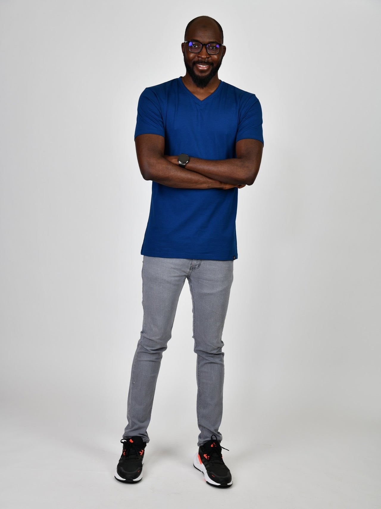 A head to toe shot of a tall and slim guy in the studio wearing a navy blue L tall slim v-neck t-shirt.