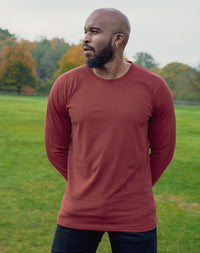 Thumbnail for A shot of a tall athletic guy in a park wearing a dark orange long sleeve tall t-shirt, looking to the right.