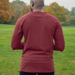 A shot from behind of a tall athletic guy wearing a long sleeve navy tall t-shirt.