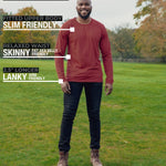 A head to toe shot of a tall athletic guy in a park wearing a dark orange long sleeve tall t-shirt.