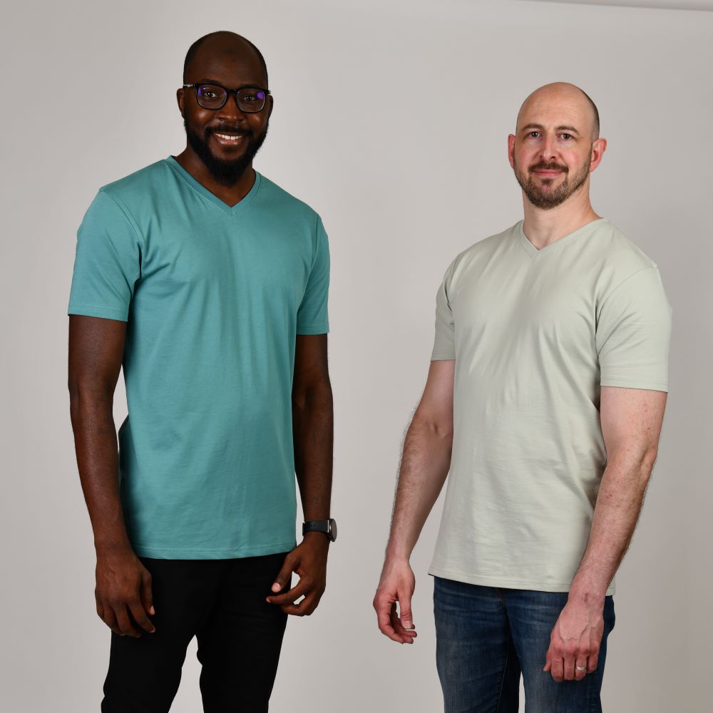 Two tall slim men wearing plain tall v-neck t-shirts in teal and sage green.