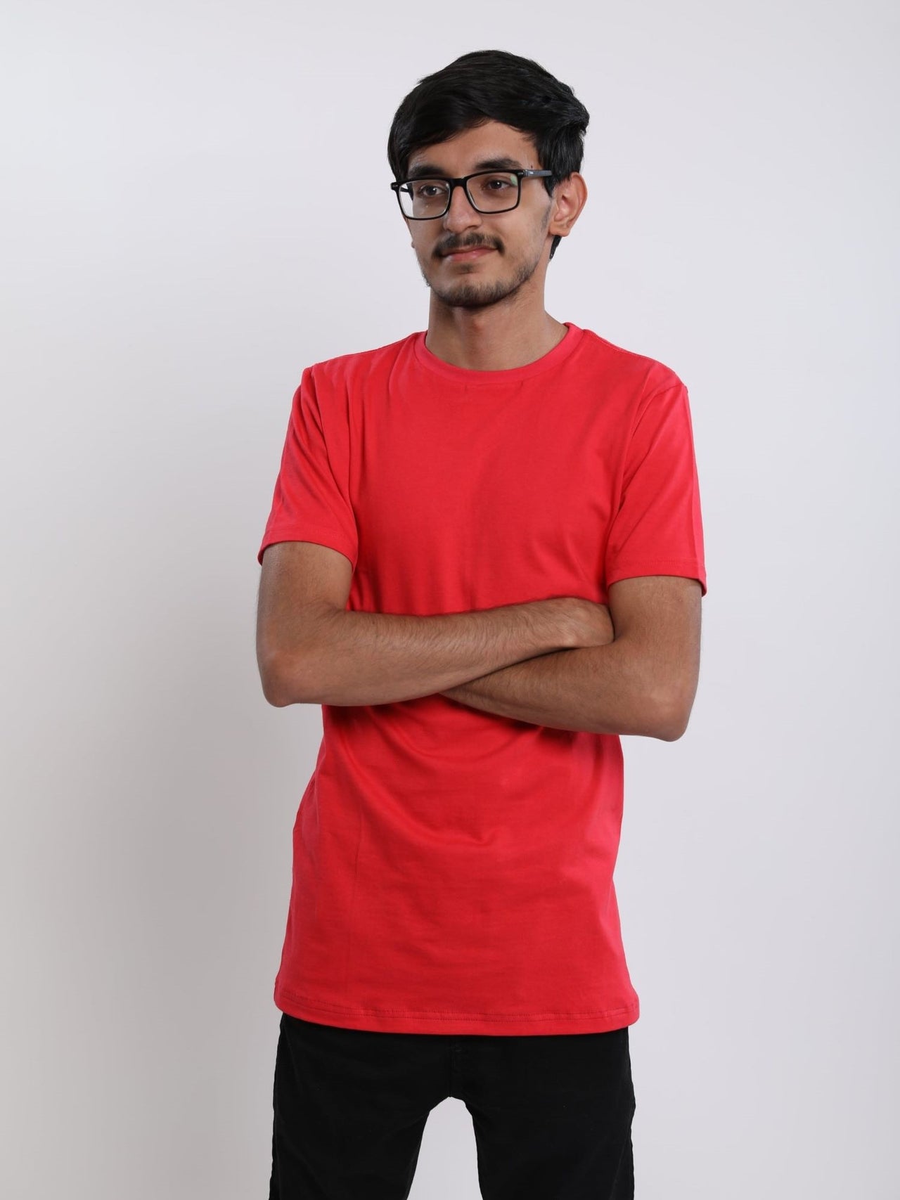 A tall skinny guy in the studio with his arms folded and wearing a red small tall slim t-shirt.