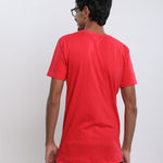 A shot from behind of a tall skinny guy in the studio wearing a red small tall slim t-shirt.