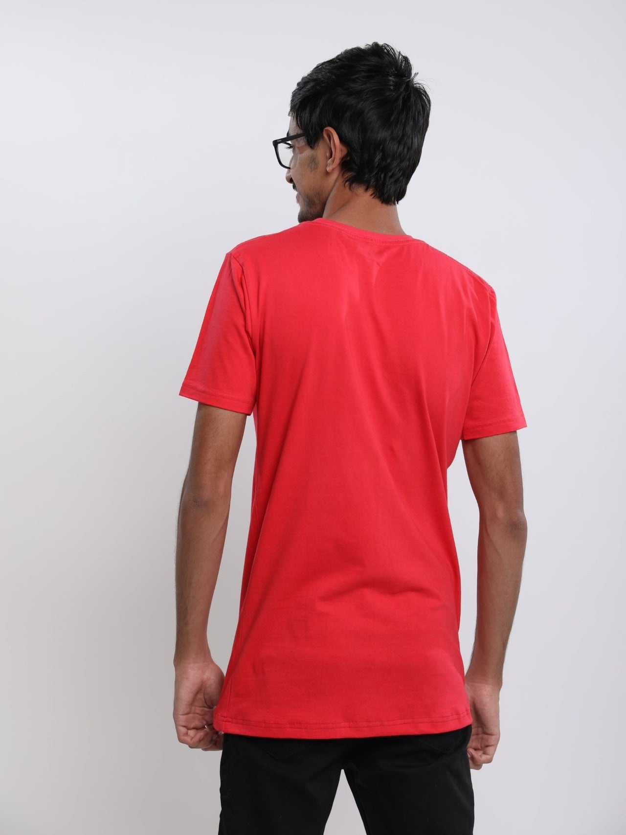 A shot from behind of a tall skinny guy in the studio wearing a red small tall slim t-shirt.