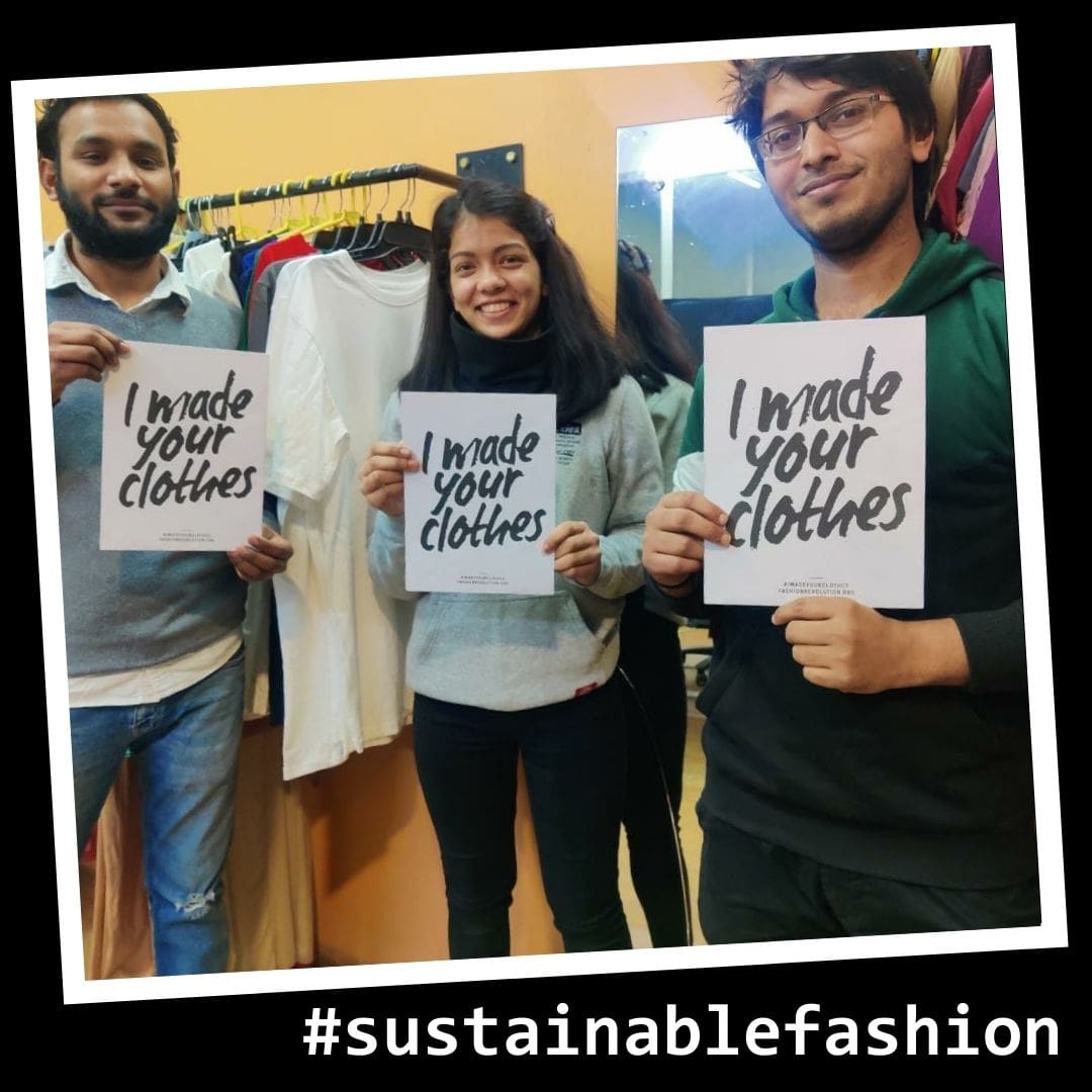 A sustainable fashion picture showing smiling employees in an ethical Indian factory holding up signs that say: 'I made your clothes'.