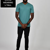 A head to toe shot of a tall and slim guy in the studio wearing a teal L tall slim v-neck t-shirt.