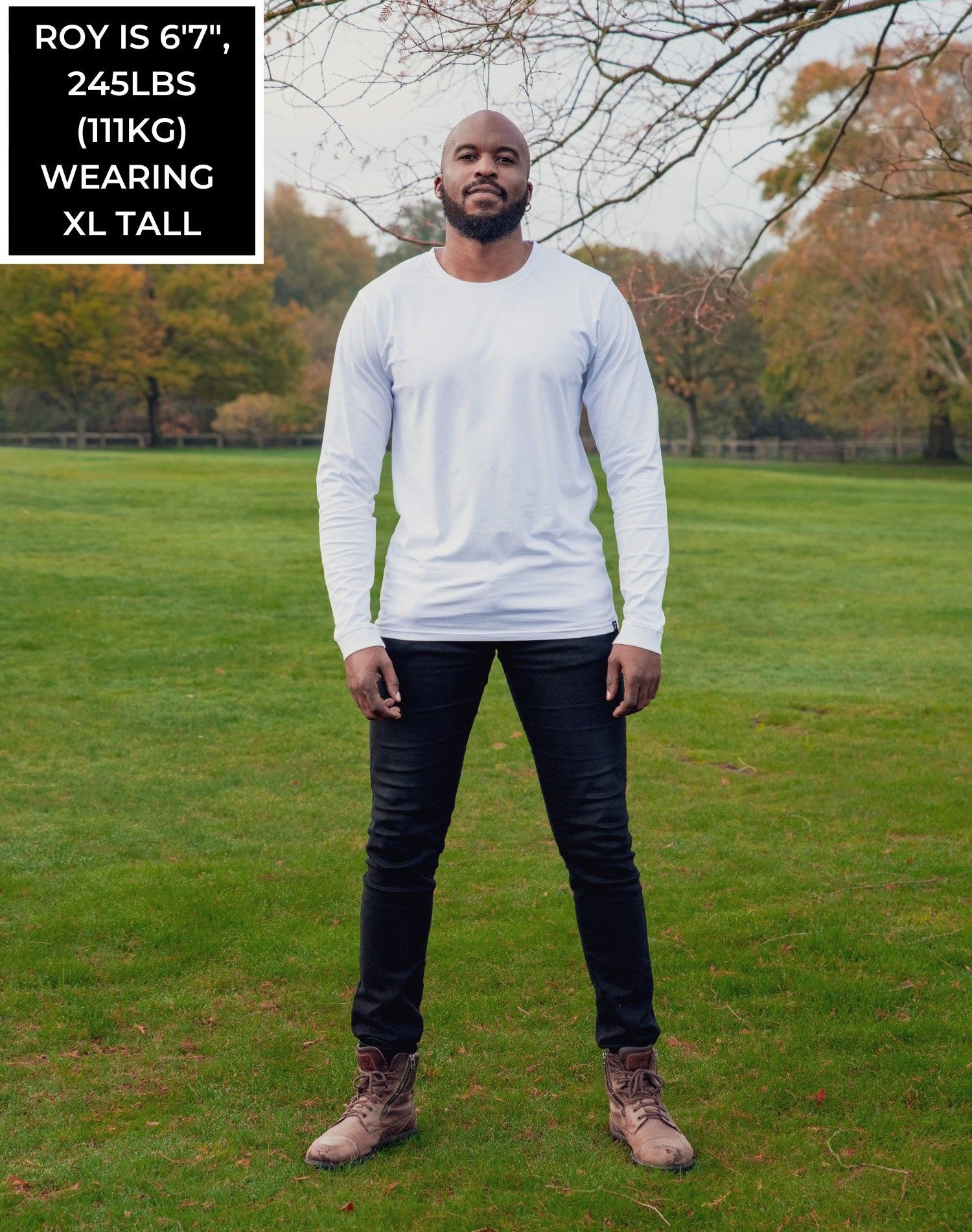 A head to toe shot of a tall athletic guy in a park wearing a white long sleeve tall t-shirt.