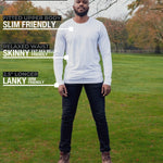 A head to toe shot of a tall athletic guy in a park wearing a white long sleeve tall t-shirt.