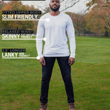 A head to toe shot of a tall athletic guy in a park wearing a white long sleeve tall t-shirt.