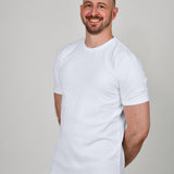 A tall and slim guy in the studio, hands behind back and wearing a white XL tall slim fit t-shirt.