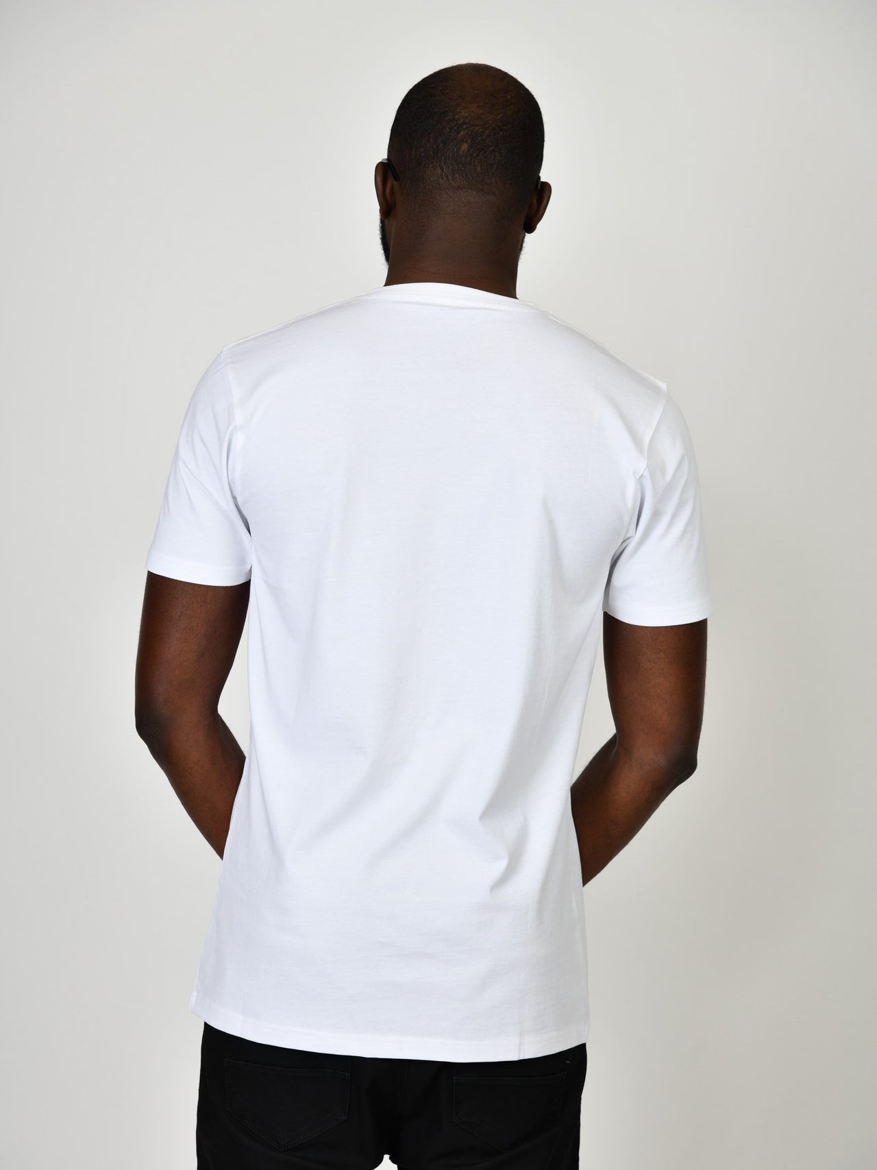 A shot from behind of a tall and slim guy in the studio and wearing a white L tall slim v-neck t-shirt.