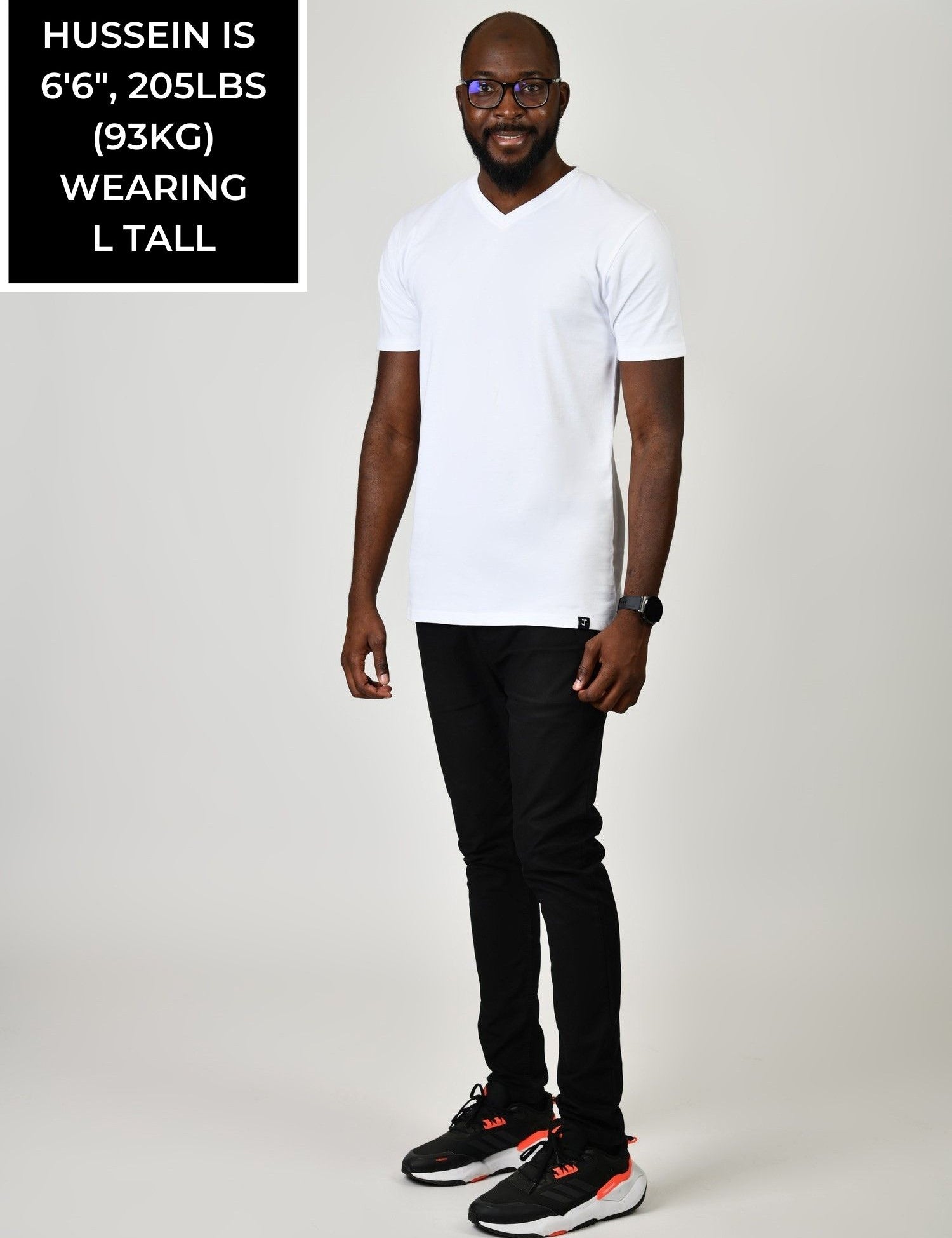 A head to toe shot of a tall and slim guy in the studio wearing a white L tall slim v-neck t-shirt.