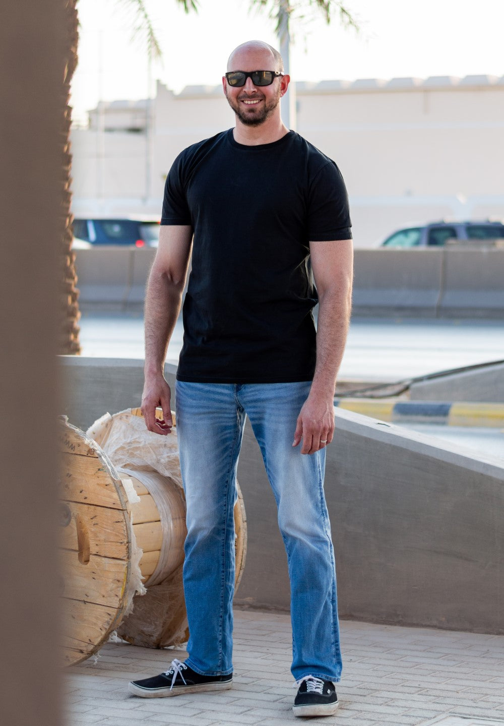 A tall skinny guy on a busy street wearing an XL tall black t-shirt.
